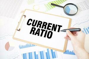 Text CURRENT RATIO on white paper sheet and marker on businessman hand on the diagram. Business concept photo