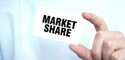 Man in blue sweatshirt holding a card with text MARKET SHARE, business concept photo