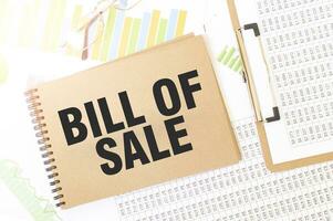 Business up graph on a sheet of craft colour Notepad with BILL OF SALE sign. Notepad on desk with financial documentation photo