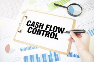 Text CASH FLOW CONTROL on white paper sheet and marker on businessman hand on the diagram. Business concept photo