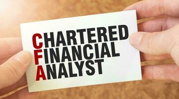 CHARTERED FINANCIAL ANALYST word inscription on white card paper sheet in hands of a businessman. photo