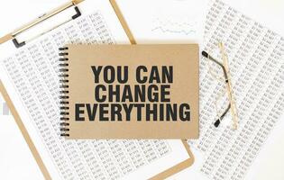 Craft colour notepad with text YOU CAN CHANGE EVERYTHING. Notepad with eyeglasses and text documents. Business concept photo