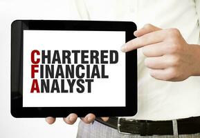 Text CHARTERED FINANCIAL ANALYST on tablet display in businessman hands on the white background. Business concept photo