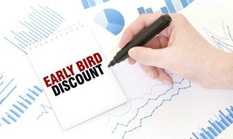Businessman holding a black marker, notepad with text EARLY BIRD DISCOUNT, business concept photo