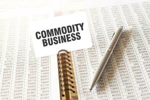 Text COMMODITY BUSINESS on paper card, pen, financial documentation on table photo