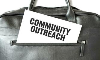 Text COMMUNITY OUTREACH writing on white paper sheet in the black business bag. Business concept photo