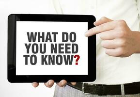 Text WHAT DO YOU NEED TO KNOW on tablet display in businessman hands on the white background. Business concept photo