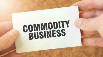 COMMODITY BUSINESS word inscription on white card paper sheet in hands of a businessman. photo