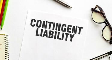 CONTINGENT LIABILITY on paper with glasses and pen photo