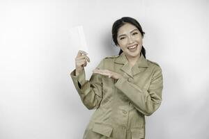 un contento joven hermosa asiático trabajador vistiendo marrón uniforme participación un sobre. indonesio pns concepto. foto