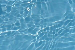 Blue water with ripples on the surface. Defocus blurred transparent blue colored clear calm water surface texture with splashes and bubbles. Water waves with shining pattern texture background. photo