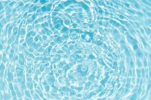 Blue water with ripples on the surface. Defocus blurred transparent blue colored clear calm water surface texture with splashes and bubbles. Water waves with shining pattern texture background. photo