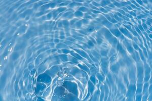 Blue water with ripples on the surface. Defocus blurred transparent blue colored clear calm water surface texture with splashes and bubbles. Water waves with shining pattern texture background. photo