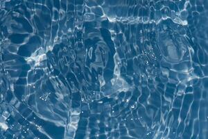 Blue water with ripples on the surface. Defocus blurred transparent blue colored clear calm water surface texture with splashes and bubbles. Water waves with shining pattern texture background. photo