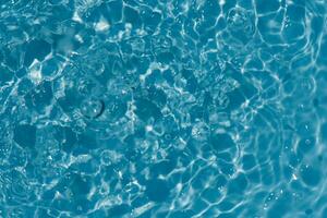 Blue water with ripples on the surface. Defocus blurred transparent blue colored clear calm water surface texture with splashes and bubbles. Water waves with shining pattern texture background. photo