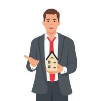 Young business man holding home model and presenting with hand and pointing with finger. vector