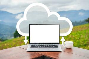 Empty screen laptop with cup of coffee with mountain view and mist in the morning, Cloud computing concept photo