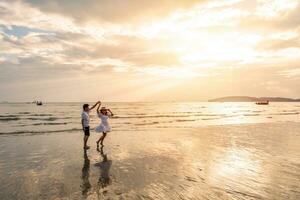 Young woman traveler holding man's hand and looking beautiful sunset on the beach, Couple on vacation in summer concept photo