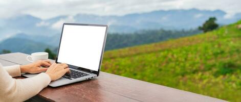 Young woman freelancer traveler working online using laptop and enjoying the beautiful nature landscape with mountain view photo