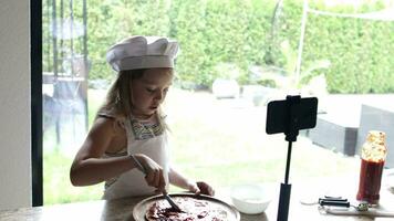 Girl of 6 years old is preparing pizza with tomatoes sauce and violet onion in front of her subscribers. video