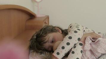 uma pequeno menina é dormindo dentro a cama e segurando uma boneca video