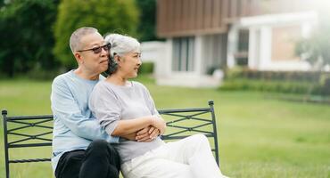 Asian senior couple having a good time. They laughing and smiling while sitting outdoor at the park. Lovely senior couple photo