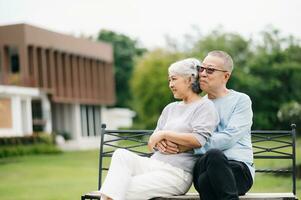 Asian senior couple having a good time. They laughing and smiling while sitting outdoor at the park. Lovely senior couple photo