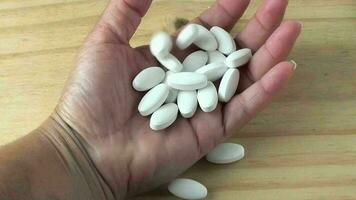 White medicine or supplement pills thrown into the palm hand video