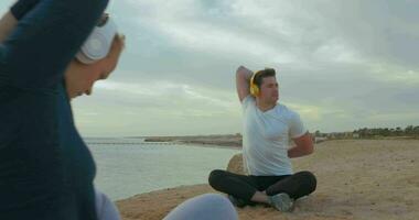 Young people in headphones working out by the sea video