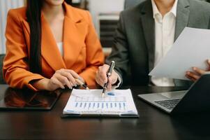 Business documents on office table with smart phone and calculator digital tablet and graph business with social network diagram and two colleagues discussing data working in the office photo