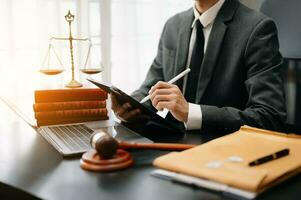 justice and law concept. Male judge in a courtroom the gavel, working with smart phone and laptop and digital tablet computer on white table photo