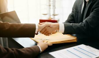 Man lawyer hand and women client shaking hand collaborate on working agreements with contract documents at the office. photo