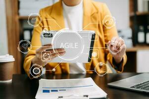 ágil desarrollo metodología concepto. negocio mano utilizando ordenador portátil computadora y tableta con virtual pantalla ágil icono en moderno oficina digital tecnología concepto. foto