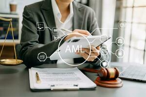 AML Anti Money Laundering Financial Bank Business Concept. judge in a courtroom using laptop and tablet with AML anti money laundering icon on virtual  screen. photo