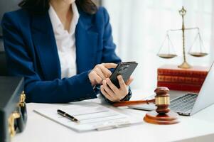 justice and law concept. Female judge in a courtroom the gavel, working with smart phone and laptop and digital tablet computer on white table photo
