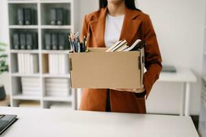 woman office worker celebrating her resignation, carrying her personal stuff. leaving job, changing or company.in nodern office photo