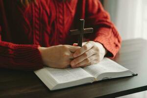 mujer sentada y estudiando las escrituras. la cruz de madera en las manos. conceptos de educación cristiana las sagradas escrituras abiertas foto