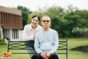 Happy adult granddaughter and senior grandfather having fun enjoying talk while relaxing sitting outdoor in the park photo