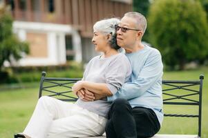 asiático mayor Pareja teniendo un bueno tiempo. ellos riendo y sonriente mientras sentado al aire libre a el parque. encantador mayor Pareja foto