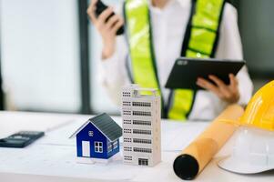 Engineer in helmet for workers security on office buildings and management on the construction drawing plan near laptop working in Engineering tools on table photo