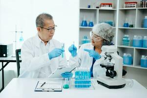 Two scientist or medical technician working, having a medical discuss meeting with Asian senior female scientist supervisor in the laboratory with online reading, test samples and innovation photo