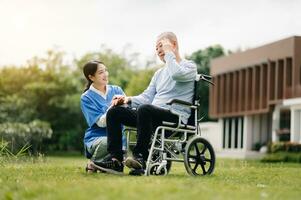 Elderly asian senior man on wheelchair with Asian careful caregiver. Nursing home hospital garden concept are walking in the garden. to help and encourage. photo