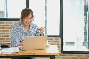 Beautiful young teen Asian business woman using computer laptop with hands up in winner is a gesture, Happy to be successfully celebrating achievement success. photo