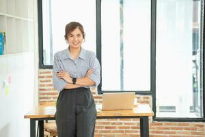 Portrait of a woman business owner showing a happy smiling face as he has successfully invested in her business using tablets and financial budget documents at work. photo