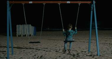 solitaire enfant balançant sur le plage à nuit video