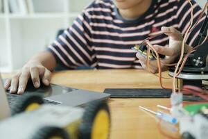 Asian teenager doing robot project in science classroom. technology of robotics programing and STEM education concept. photo