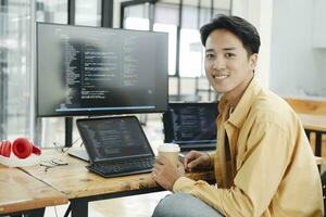 Young programmer working on desktop PC in office of software company. photo