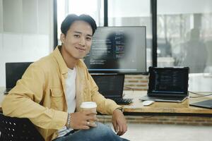 Young programmer working on desktop PC in office of software company. photo