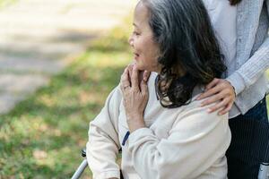 Family relationship Asian senior woman in wheelchair with happy daughter holding caregiver for a hand while spending time together photo