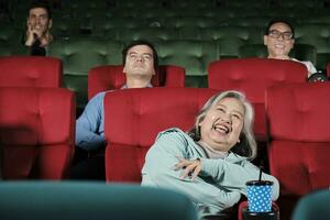 Various people enjoy watching comedy cinema in movie theaters. Senior Asian woman and audiences have a fun indoor entertainment lifestyle with film art shows, happy and cheerful with drink and smiles. photo